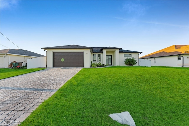 prairie-style house featuring a front yard, an attached garage, fence, and driveway