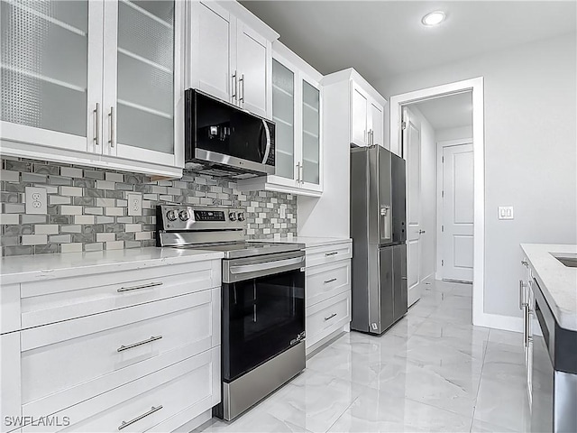 650 Kraft St, Lehigh Acres, FL 33974 - kitchen with appliances with stainless steel finishes, baseboards, decorative backsplash, light marble finish floors, and white cabinetry