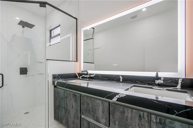 full bath with double vanity, visible vents, a marble finish shower, and a sink