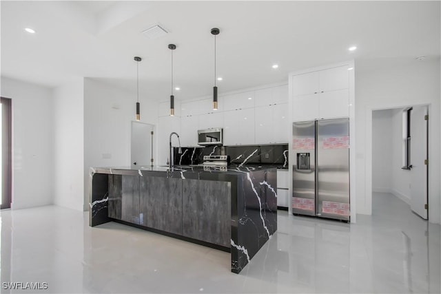 kitchen with appliances with stainless steel finishes, pendant lighting, white cabinetry, dark countertops, and modern cabinets