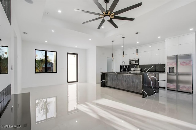 interior space featuring open floor plan, appliances with stainless steel finishes, white cabinetry, a raised ceiling, and modern cabinets