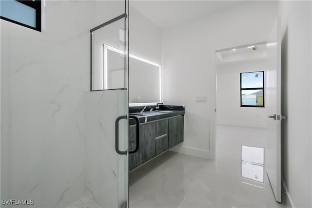 bathroom with a sink, a marble finish shower, baseboards, and double vanity