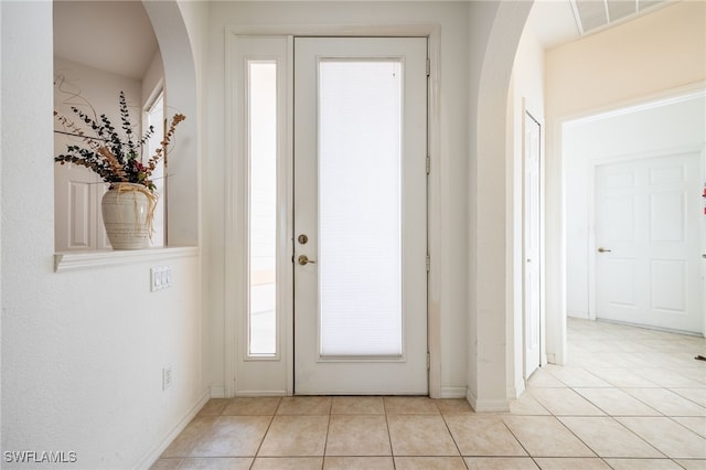 tiled entrance foyer featuring visible vents, arched walkways, and baseboards