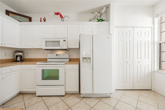 kitchen with light tile patterned floors, white cabinets, white appliances, and light countertops