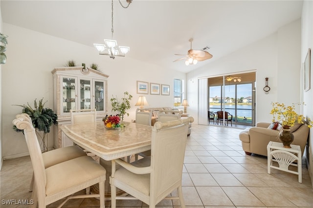 dining space with light tile patterned floors, ceiling fan with notable chandelier, lofted ceiling, and a water view