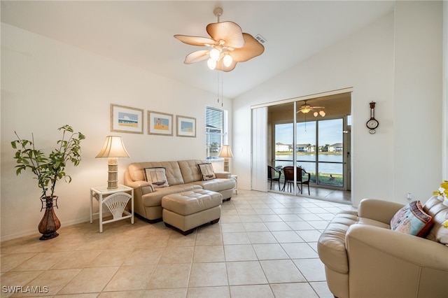 living area with light tile patterned flooring, baseboards, a ceiling fan, and a water view