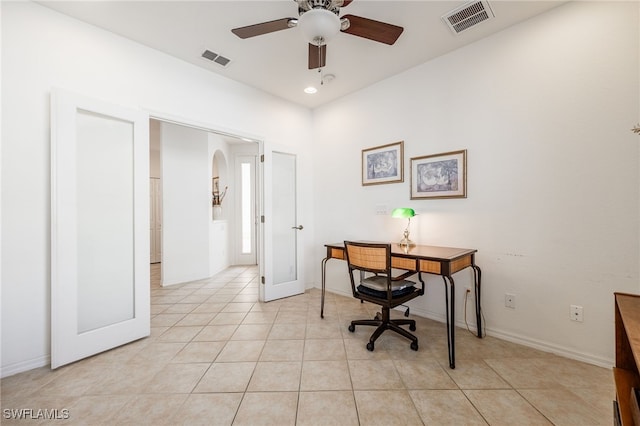 office with light tile patterned floors, visible vents, arched walkways, and a ceiling fan