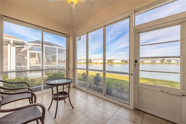 sunroom featuring a ceiling fan, a water view, and a healthy amount of sunlight