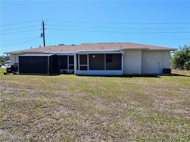 back of house featuring a yard, central AC unit, stucco siding, and a sunroom