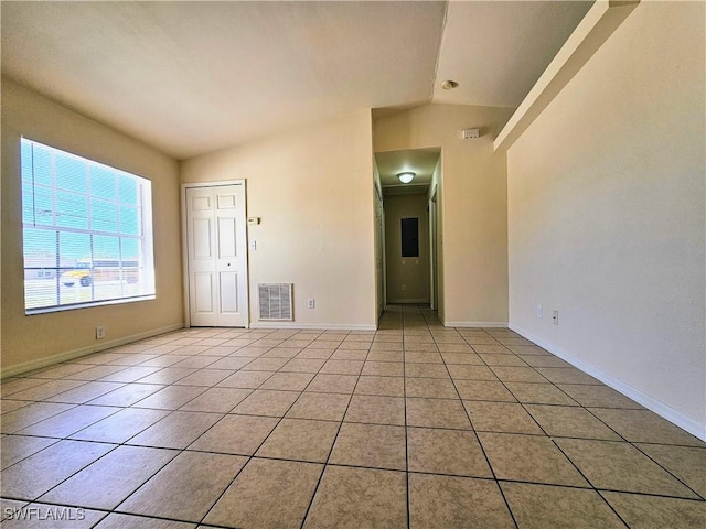 spare room with vaulted ceiling, light tile patterned floors, baseboards, and visible vents