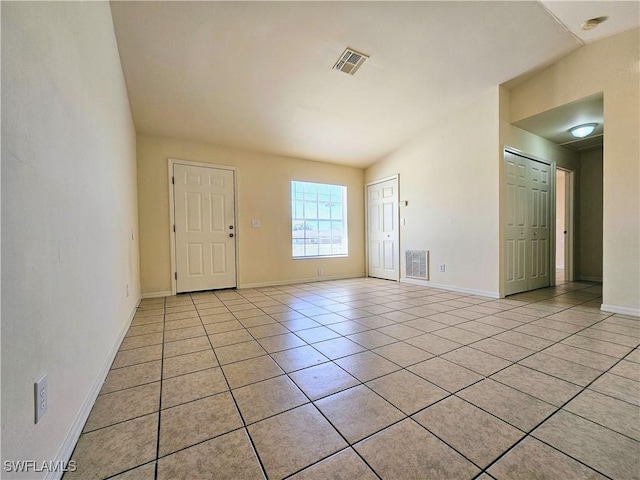 spare room featuring light tile patterned floors, visible vents, and baseboards