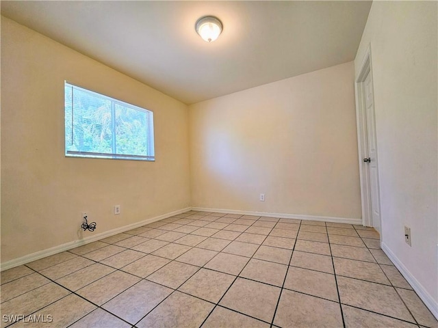 empty room featuring light tile patterned flooring and baseboards