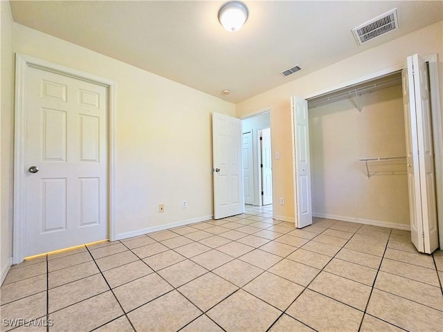 unfurnished bedroom with light tile patterned floors, visible vents, baseboards, and a closet