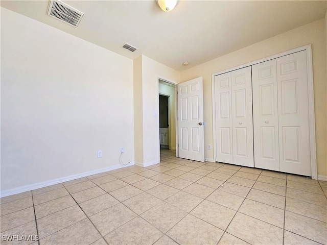 unfurnished bedroom featuring visible vents, baseboards, a closet, and light tile patterned flooring