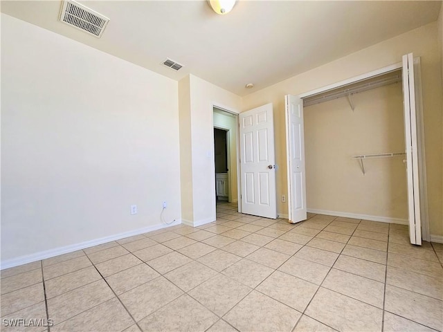 unfurnished bedroom featuring light tile patterned floors, visible vents, a closet, and baseboards