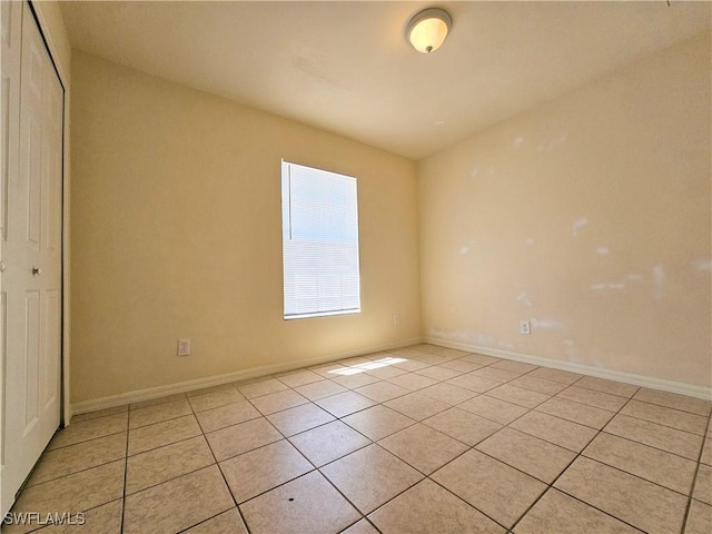 unfurnished room featuring light tile patterned flooring and baseboards