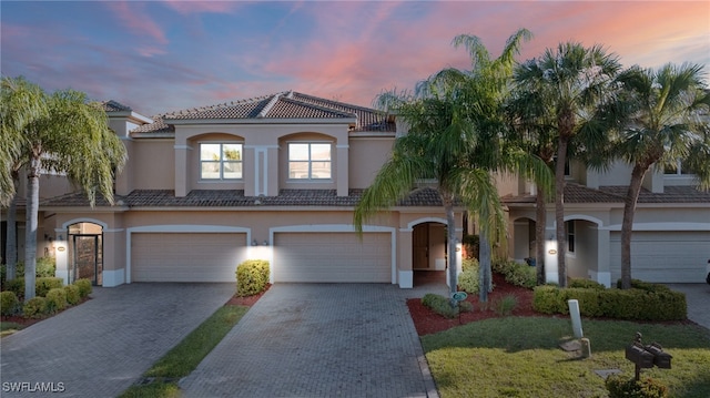 view of front of home featuring stucco siding, a tile roof, decorative driveway, and a garage