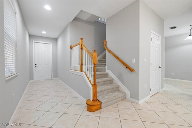 foyer entrance featuring light tile patterned floors, visible vents, baseboards, and stairs