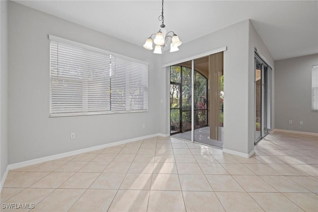 spare room with baseboards, a notable chandelier, and tile patterned flooring