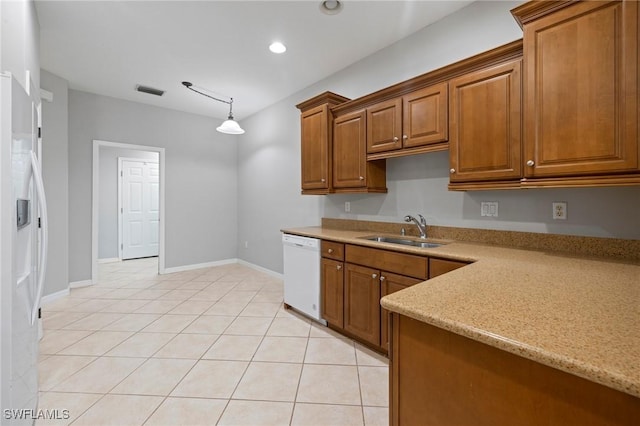 kitchen featuring refrigerator with ice dispenser, a sink, light tile patterned flooring, brown cabinetry, and white dishwasher