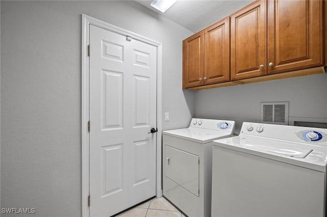 laundry area featuring separate washer and dryer, light tile patterned floors, cabinet space, and visible vents