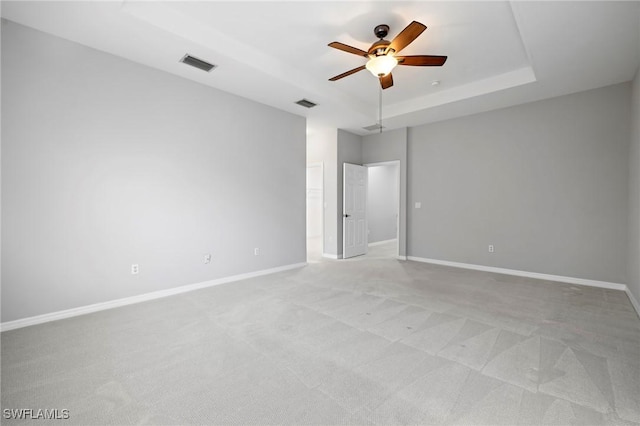 empty room with visible vents, a raised ceiling, baseboards, and ceiling fan