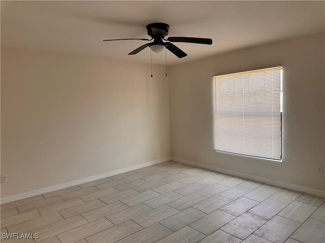 spare room with baseboards and ceiling fan