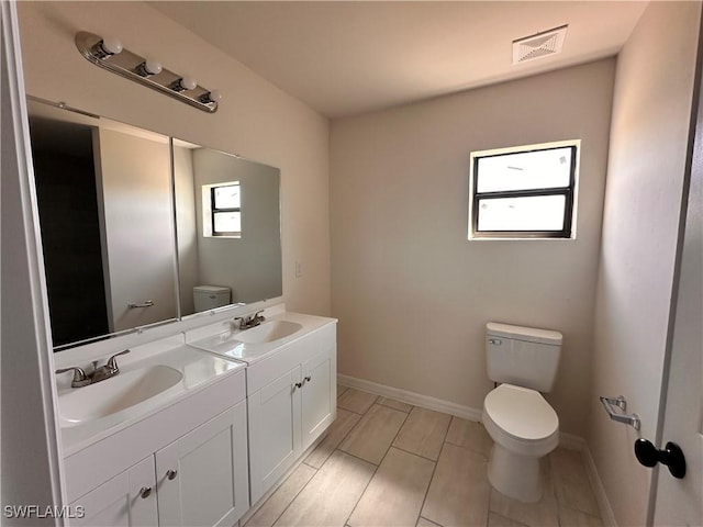 bathroom featuring visible vents, toilet, baseboards, and a sink