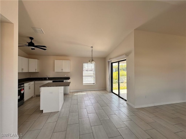 kitchen featuring visible vents, a kitchen island, dark countertops, white cabinets, and hanging light fixtures