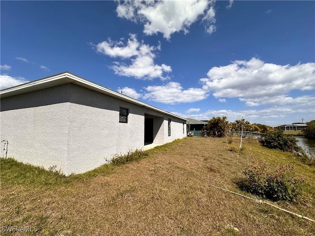 view of side of property featuring a lawn and stucco siding