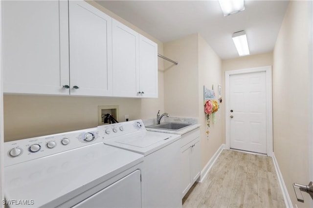 clothes washing area featuring a sink, baseboards, washer and dryer, cabinet space, and light wood-style flooring