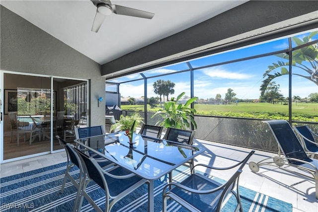 sunroom featuring a ceiling fan, golf course view, and outdoor dining area