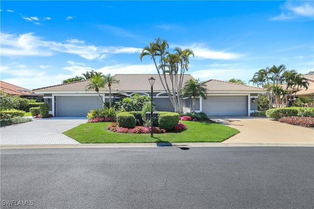 single story home with stucco siding, an attached garage, a tile roof, and driveway