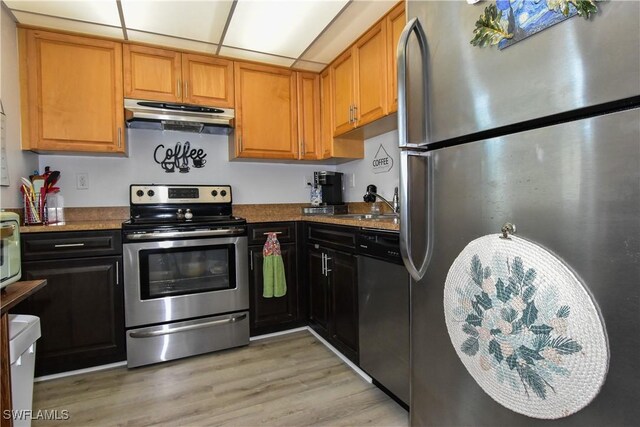 6102 Augusta Dr Unit 209, Fort Myers, FL 33907 - kitchen with brown cabinets, a sink, light wood-style floors, appliances with stainless steel finishes, and extractor fan
