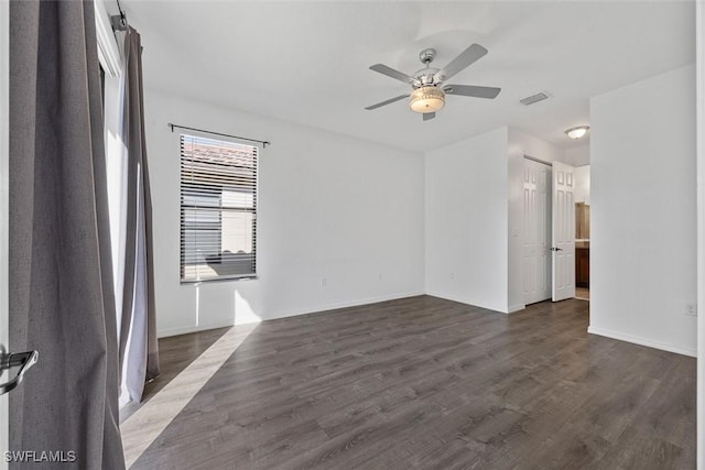 unfurnished room featuring visible vents, a ceiling fan, dark wood-style flooring, and baseboards