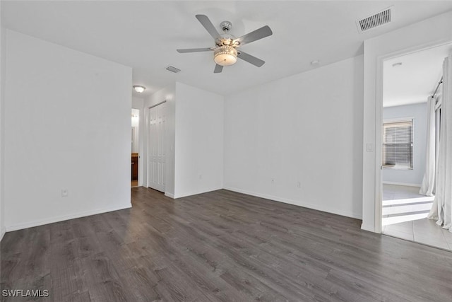 empty room featuring wood finished floors, a ceiling fan, and visible vents