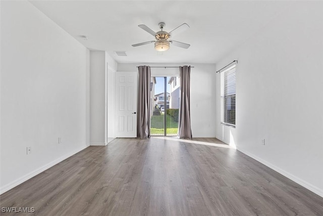 empty room featuring visible vents, baseboards, a ceiling fan, and wood finished floors