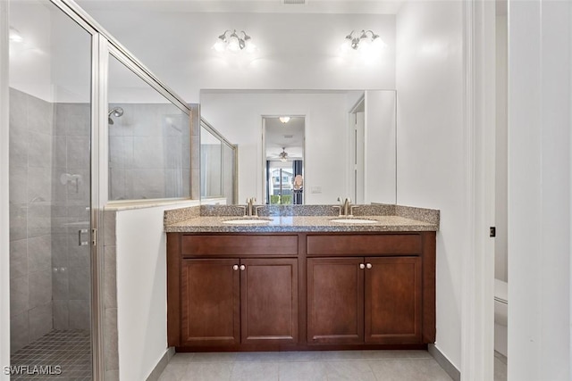 bathroom featuring a sink, double vanity, a shower stall, and tile patterned flooring