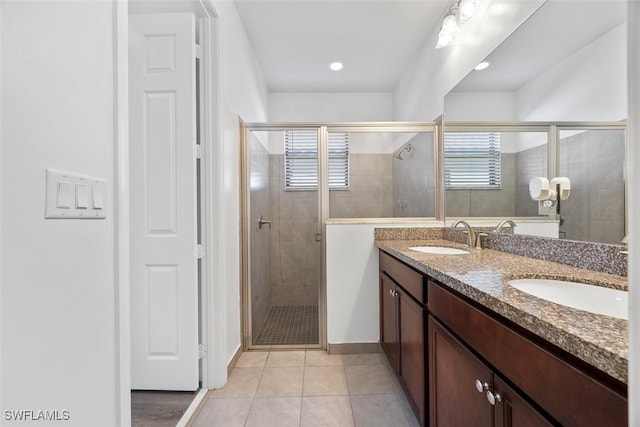 bathroom featuring a sink, double vanity, a shower stall, and tile patterned floors