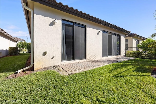 back of property with a patio area, a lawn, fence, and stucco siding