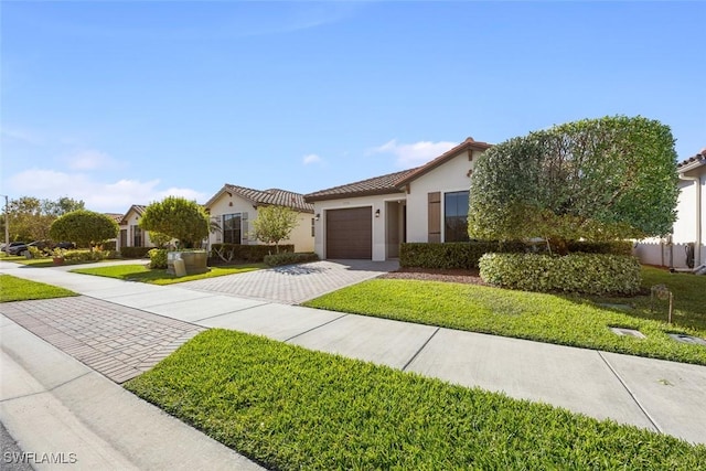 view of front of property featuring stucco siding, driveway, a front yard, an attached garage, and a tiled roof