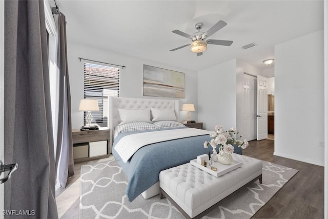 bedroom featuring wood finished floors, baseboards, visible vents, ceiling fan, and a closet