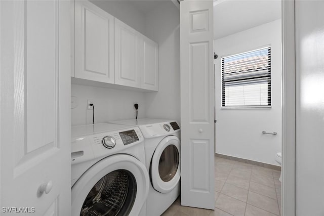 washroom with light tile patterned floors, baseboards, cabinet space, and washing machine and clothes dryer