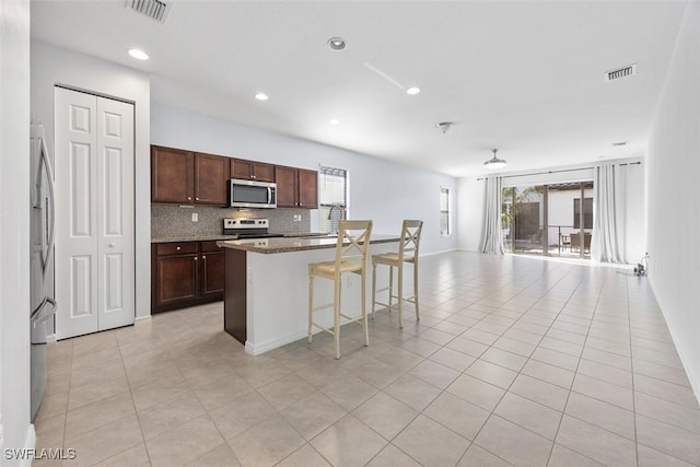 kitchen featuring visible vents, open floor plan, decorative backsplash, appliances with stainless steel finishes, and light tile patterned flooring