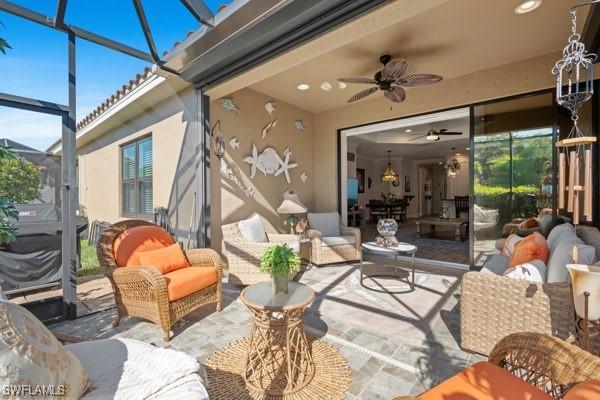 view of patio / terrace with an outdoor living space, glass enclosure, and ceiling fan