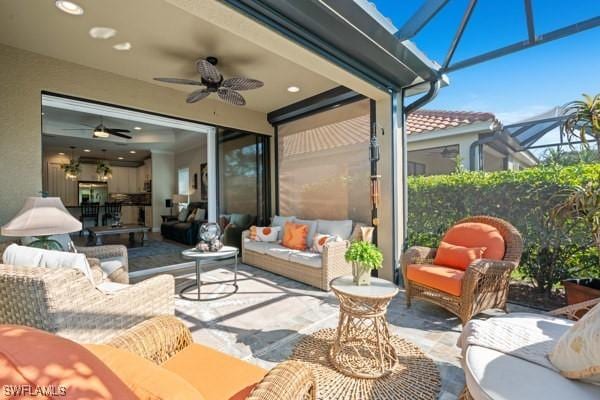 view of patio / terrace featuring glass enclosure, an outdoor hangout area, and a ceiling fan