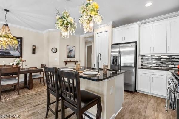 kitchen with light wood finished floors, appliances with stainless steel finishes, dark countertops, and ornamental molding