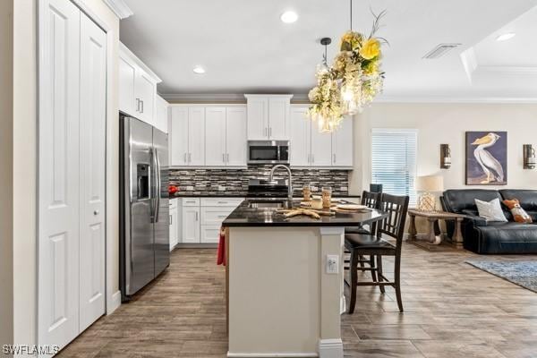 kitchen featuring a sink, dark countertops, open floor plan, appliances with stainless steel finishes, and crown molding