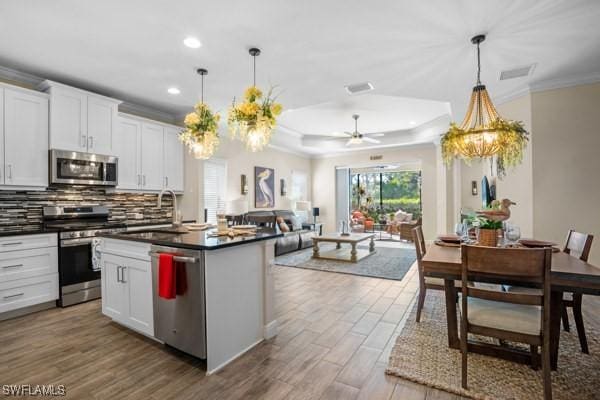 kitchen with ornamental molding, tasteful backsplash, dark countertops, wood finished floors, and stainless steel appliances