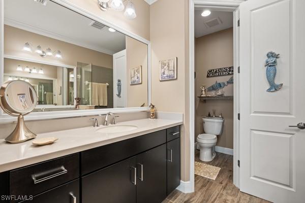 bathroom with vanity, toilet, wood finished floors, and visible vents